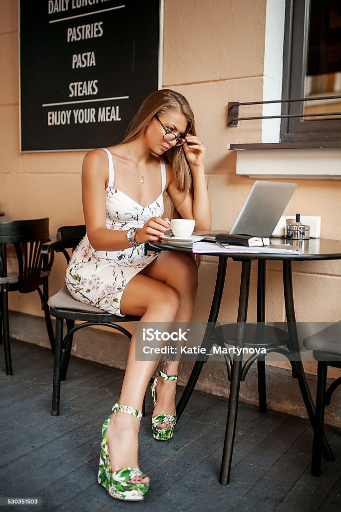 Young business woman in cafe with laptop Young business woman in cafe drinking tea / coffee working with laptop and taking notes Beautiful Woman Stock Photo