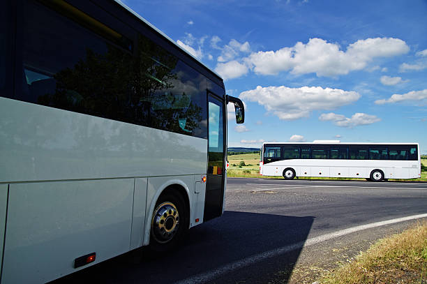 dos blanco autobuses que pasa a través de la intersección - autocar fotos fotografías e imágenes de stock