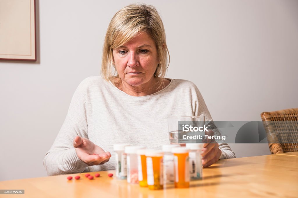 Struggling with an addiction to painkillers A middle-aged woman struggling with an addiction to painkillers or confused about her medication. Confusion Stock Photo