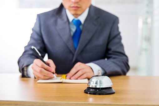 Service businessman writing at reception desk.