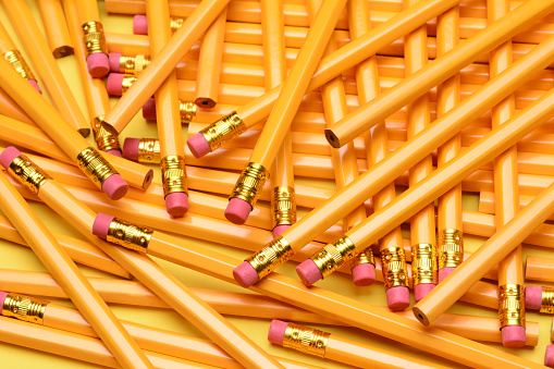 A random pile of pencils. Brand new pencils scattered on a yellow surface. Great for back to school projects.
