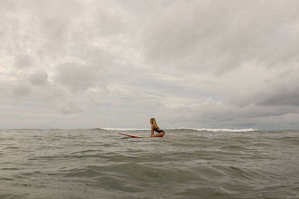chica surfista buscando olas - blond hair overcast sun sky fotografías e imágenes de stock