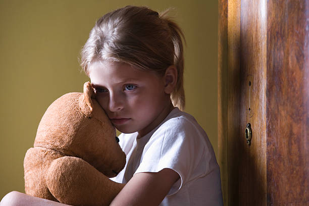 istock Girl embracing teddy bear in home 530402309