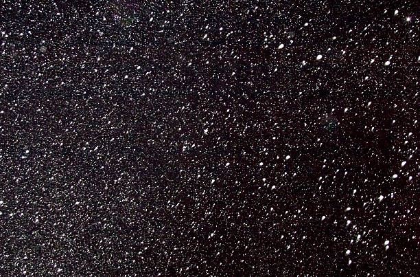 istock White flakes of snow on a black background. 530406431