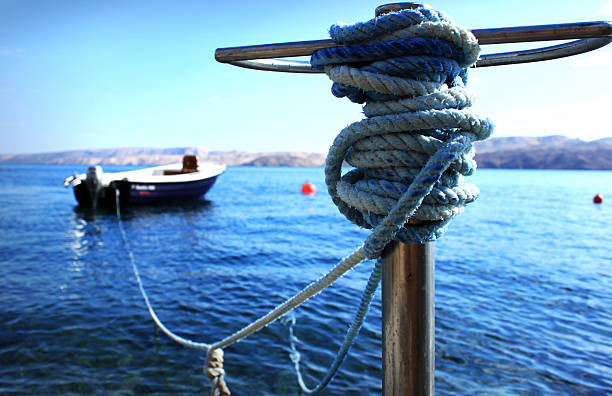 Small wooden boat tied to a metal pole on the shore.