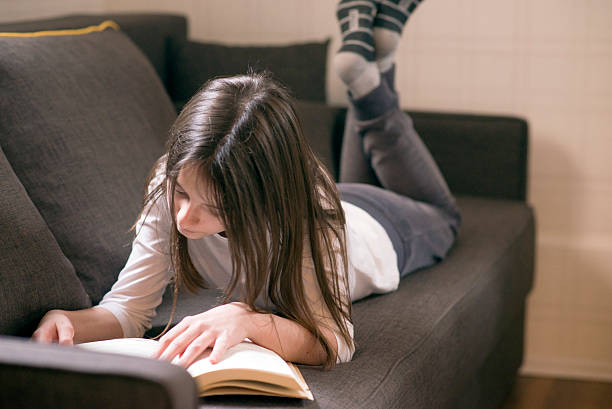 istock Girl reading a book at home 530412524
