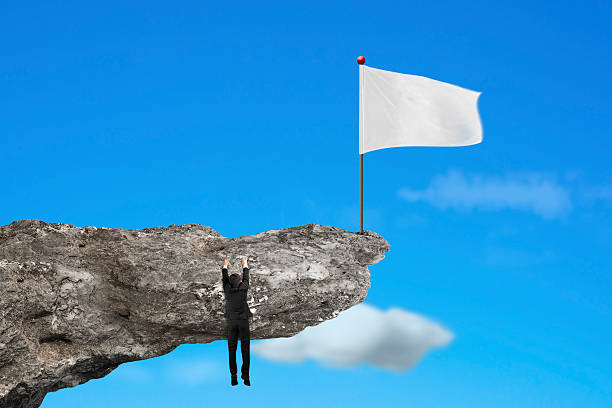 istock man hanging on cliff with blank white flag and sky 530413979