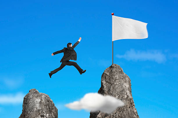 istock businessman jumping over mountain peak to blank flag with sky 530414391