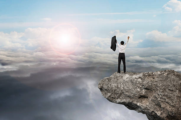 istock businessman cheering on cliff with natural sky daylight cloudsca 530415123