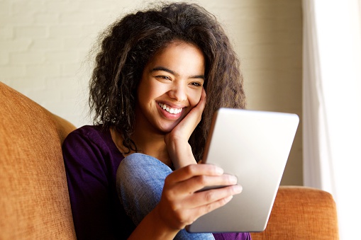 Portrait of a young woman smiling with digital tablet at home