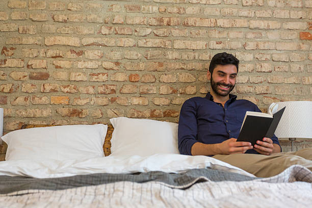 istock Smiling Man Reading a Book in His Bedroom 530416381