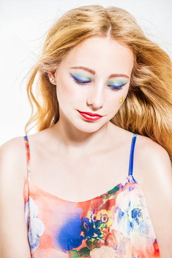 Beautiful girl in a flower top with long blonde hair and pretty make-up. Summer look. Looking down.