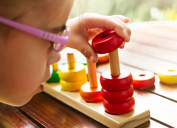 istock Visually disabled child with glasses playing with wooden stacking toy 530416648