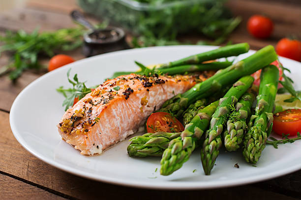 Baked salmon garnished with asparagus and tomatoes with herbs stock photo