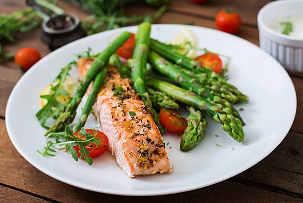 istock Baked salmon garnished with asparagus and tomatoes with herbs 530417450