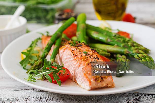 Salmón Al Horno Decorado Con Espárragos Con Hierbas Y Tomates Foto de stock y más banco de imágenes de Salmón - Pescado