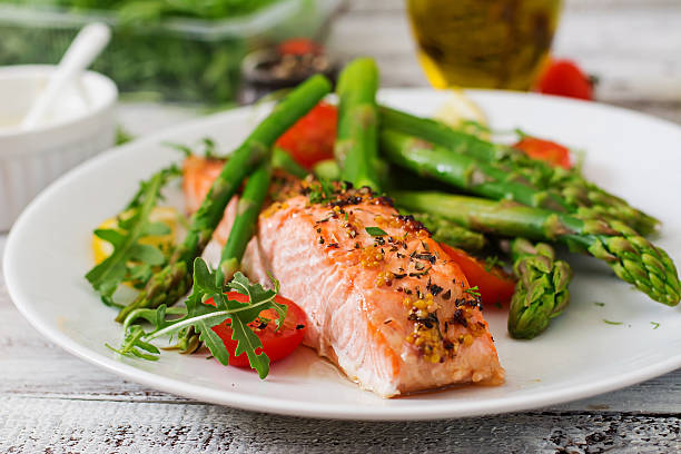 salmão assado no forno guarnecido com espargos e tomates com plantas aromáticas - modo de preparação de comida imagens e fotografias de stock