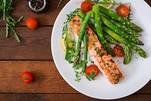 istock Baked salmon garnished with asparagus and tomatoes with herbs 530417974