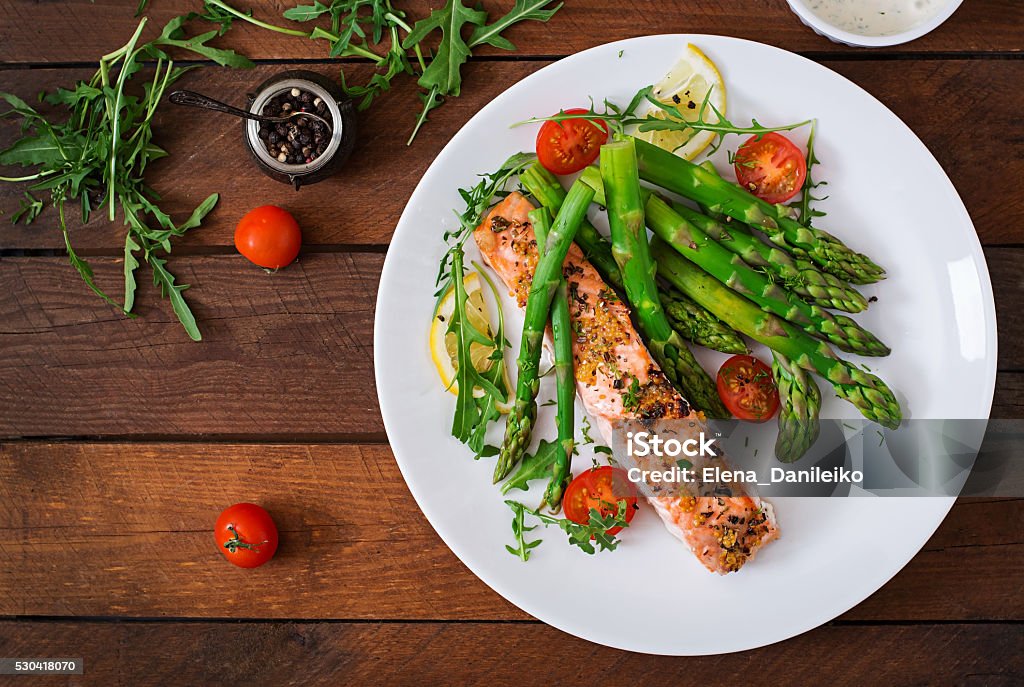 Salmón al horno decorado con espárragos con hierbas y tomates - Foto de stock de Salmón - Pescado libre de derechos