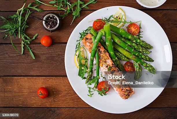 Baked Salmon Garnished With Asparagus And Tomatoes With Herbs Stock Photo - Download Image Now