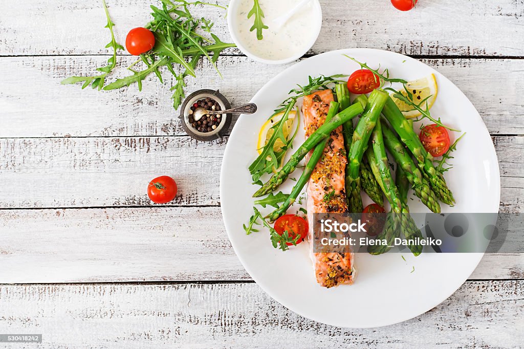 Baked salmon garnished with asparagus and tomatoes with herbs Baked salmon garnished with asparagus and tomatoes with herbs. Top view Plate Stock Photo