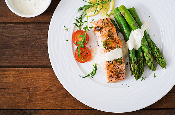 istock Baked salmon garnished with asparagus and tomatoes with herbs 530418410