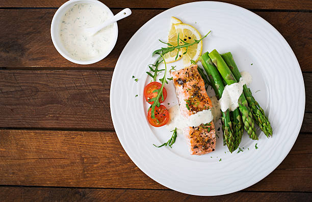 istock Baked salmon garnished with asparagus and tomatoes with herbs 530418496