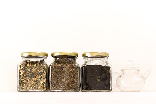 Trio of loose teas in jars, little glass teapot, and white background with lots of copy space available.