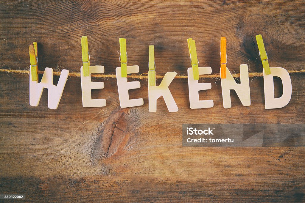 The word WEEKEND made from wooden letters The word WEEKEND made from wooden letters hunging on the rope over rustic background. retro filtered Weekend Activities Stock Photo
