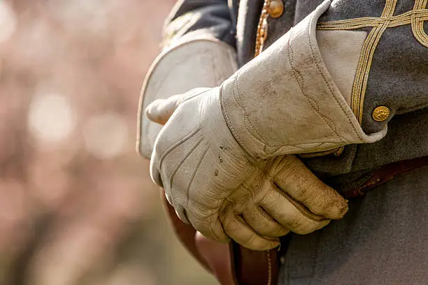 A reenactment in Virginia. A close up of the hands of an actor, showing vintage attire. Leather gloves cover the actors hands and no face is shown.