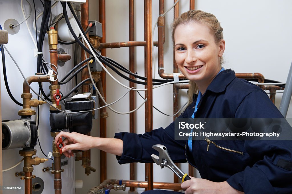 Female Plumber Working On Central Heating Boiler Plumber Stock Photo