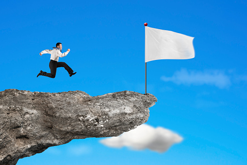 man running to blank white flag on cliff with natural sky cloud background
