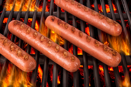 Grilled sausages over a hot barbecue grill.