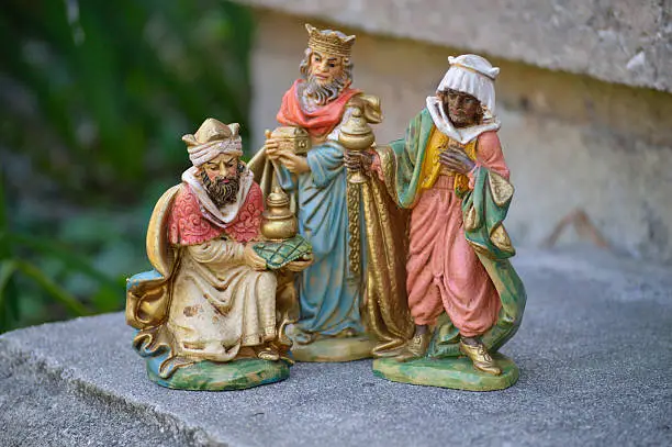 Three wise men figurines of Christ's nativity on stone steps. Christmas religious scene. Beautiful colors. Wise men with gifts of gold, frankincense and myrrh. Religious holiday background. Composition of three objects centered in photo frame.