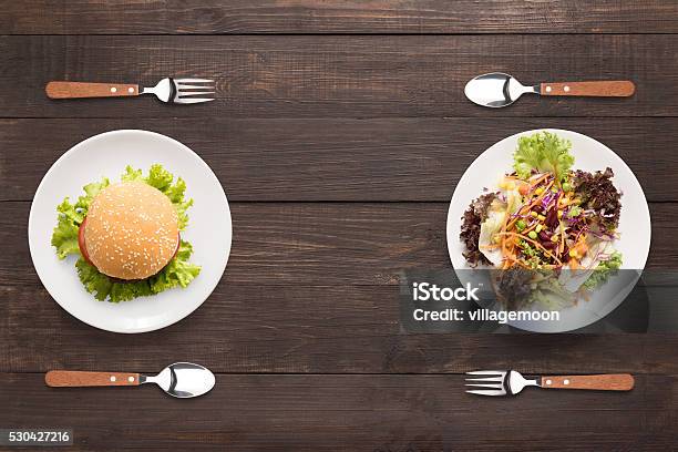 Fresh Salad And Burger On The Wooden Background Contrasting Foo Stock Photo - Download Image Now