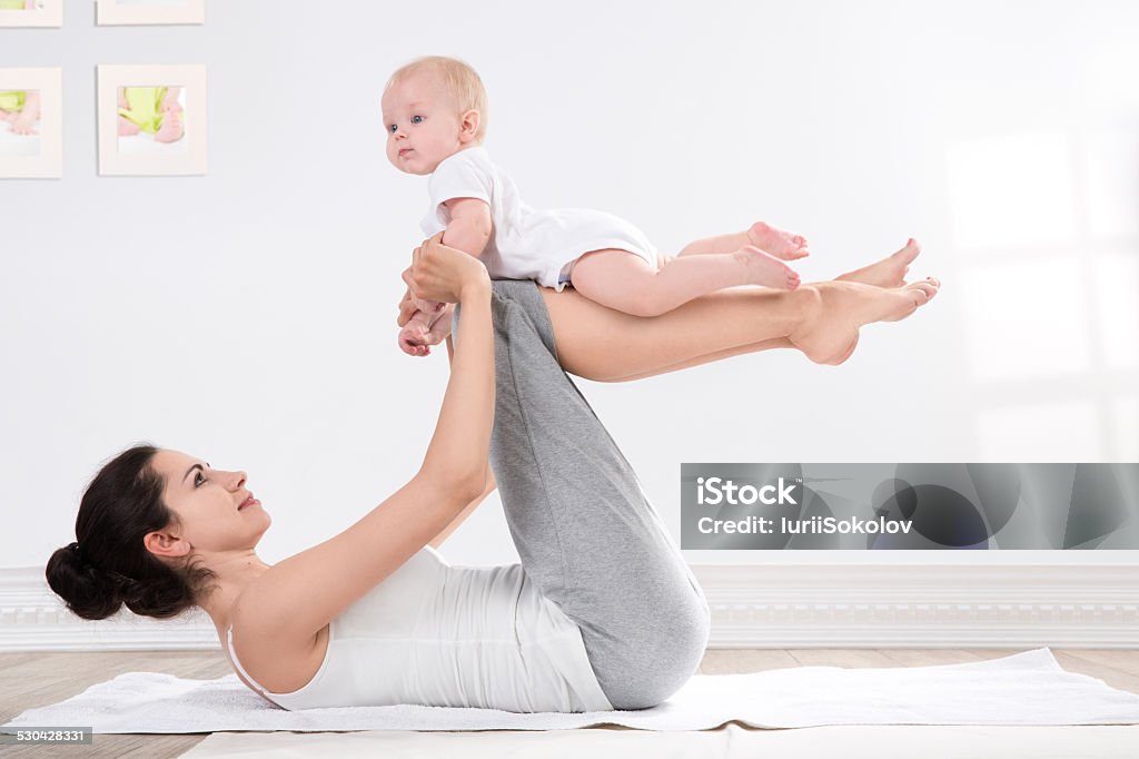 mother and baby gymnastics young mother does physical yoga exercises together with her baby Yoga Stock Photo