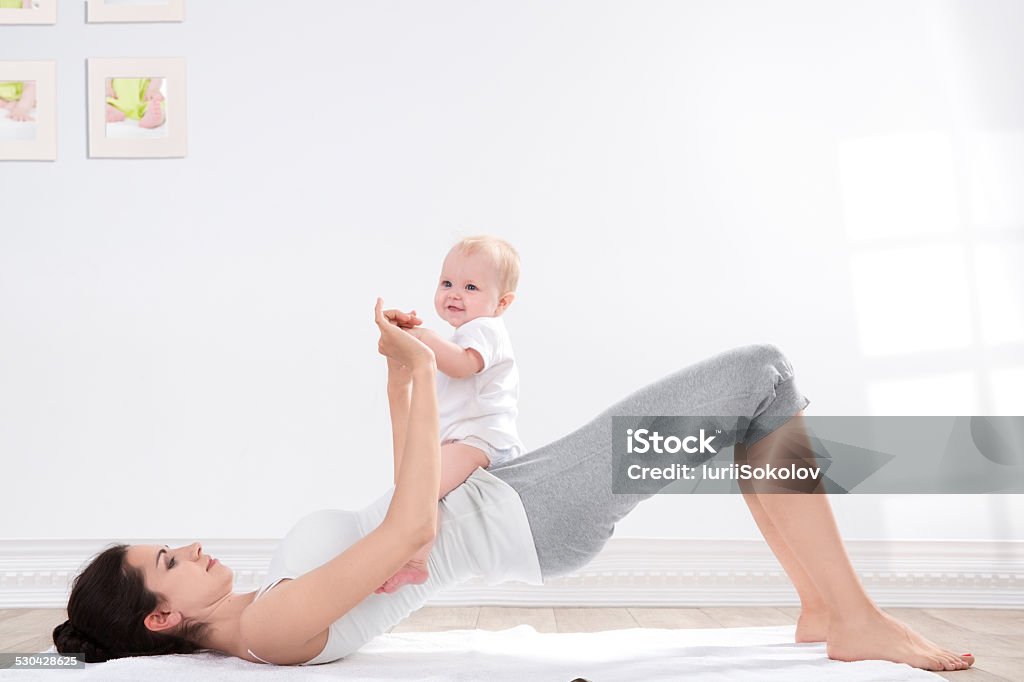 mother and baby gymnastics young mother does physical fitness exercises together with her baby Child Stock Photo