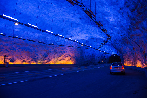 The westernmost artificial cave of the longest car tunnel in the world, called Laerdal tunnel or Lærdalstunnelen, with a car parked in the background.