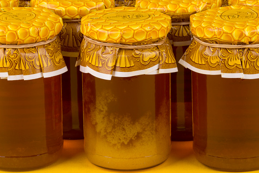 Composition with jars of honey on yellow background.