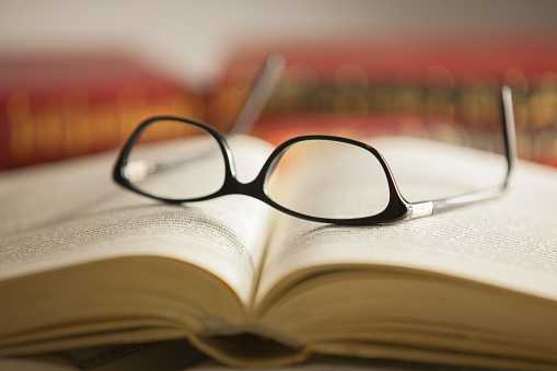 Glasses are laying on a book . Short focus picture. Focus on glasses.Books in th e Background are unsharp.