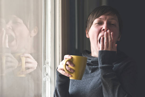 bella donna bere caffè e sbadigliare - yawning women drink coffee cup foto e immagini stock