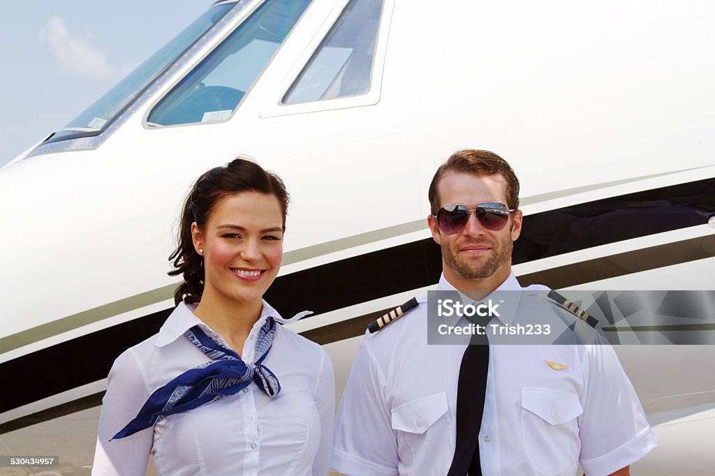Pilot and stewardess ready for passengers Pilot and stewardess standing by plane ready for passengers Adult Stock Photo
