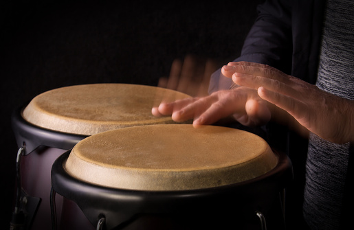 Motion Picture of a bongo Player. Black background.Picture is toned.