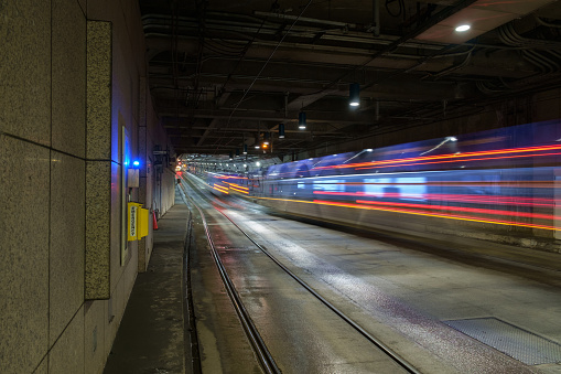 Buses move through an underground transit tunnel creating multi-colored streaks