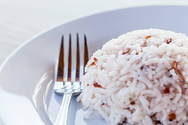 Some images of rice with fork in white dish on brown wood table