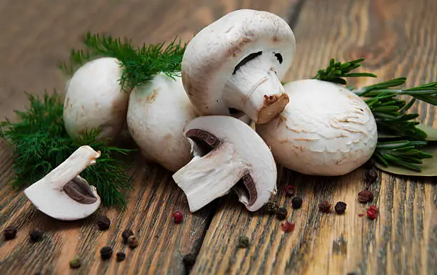 Champignon mushrooms,herbs and spices on a wooden background .
