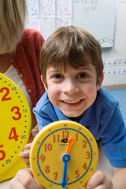 istock Boy Showing Yellow Clock With Teacher In Background 530448661