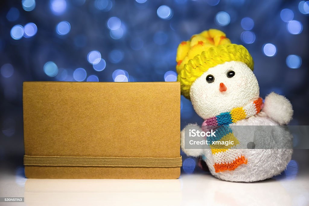 Christmas snowman toy and greeting blank card Christmas snowman toy and greeting brown blank card from craft paper with blurred Christmas lights on background Art And Craft Stock Photo