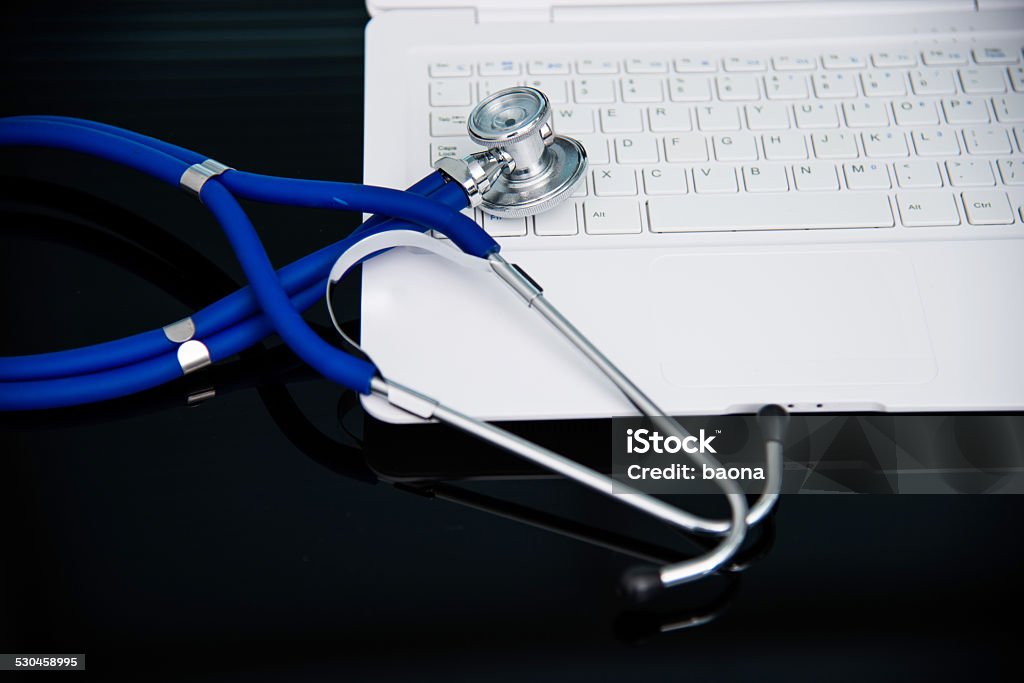 Laptop and stethescope Stethescope on the keyboard of laptop. Blue Stock Photo