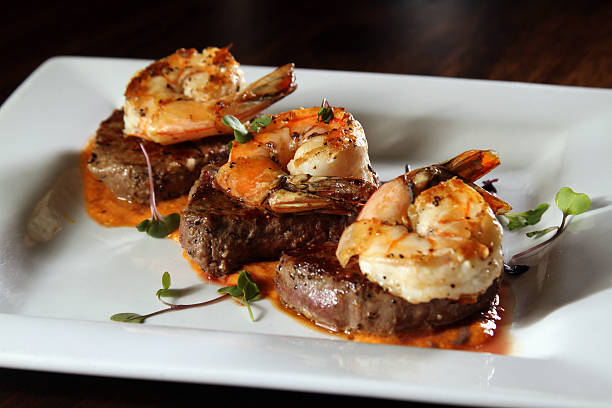 gourmet de surf and turf sobre placa blanca - surf and turf prepared shrimp steak grilled fotografías e imágenes de stock